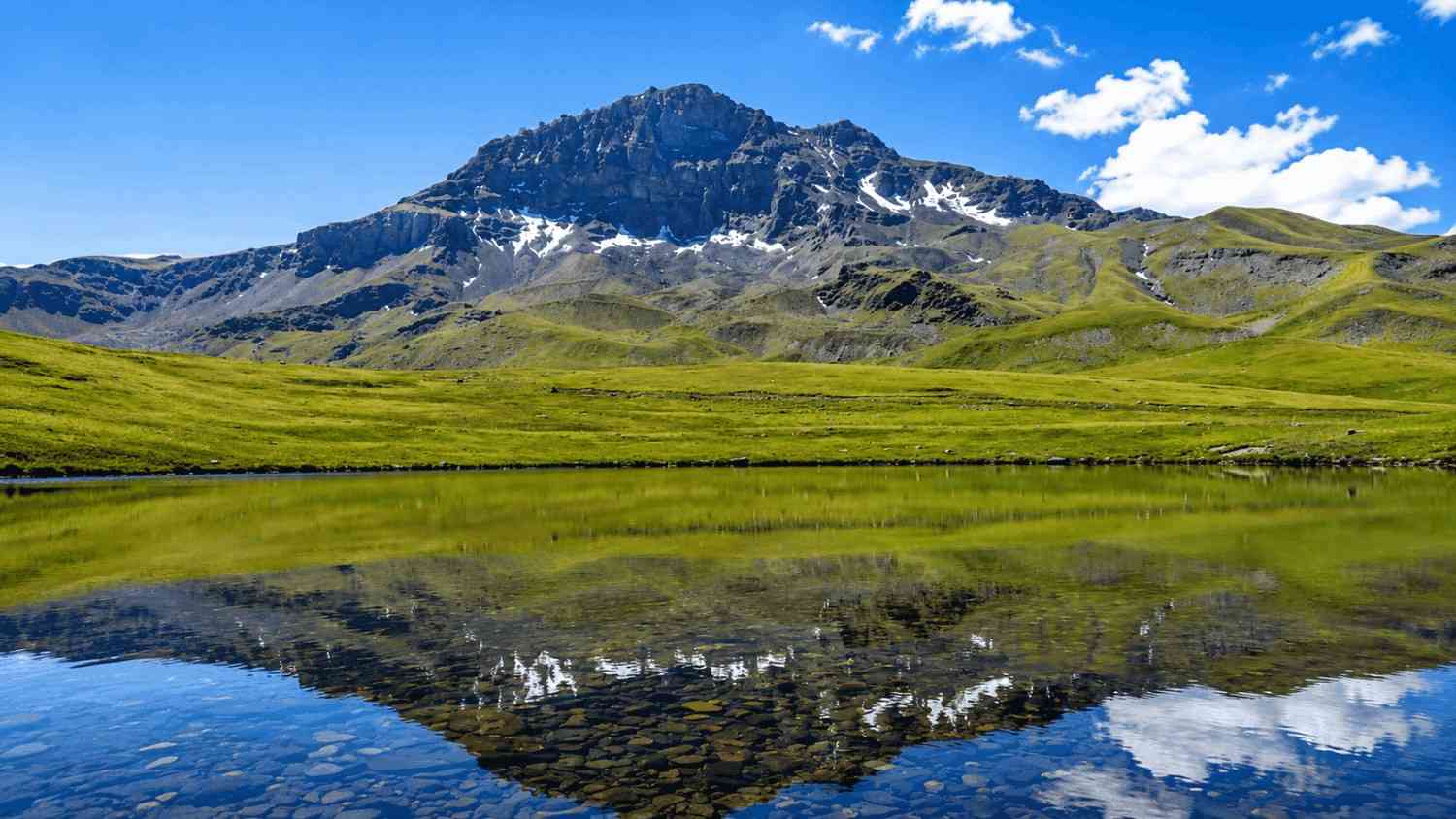 Mountain light reflecting across quiet water near Rapi Lake